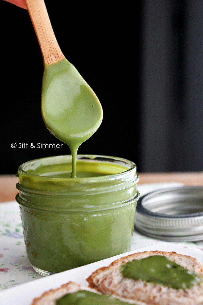 Spoon dripping Matcha Milk Green Tea Spread into jar.