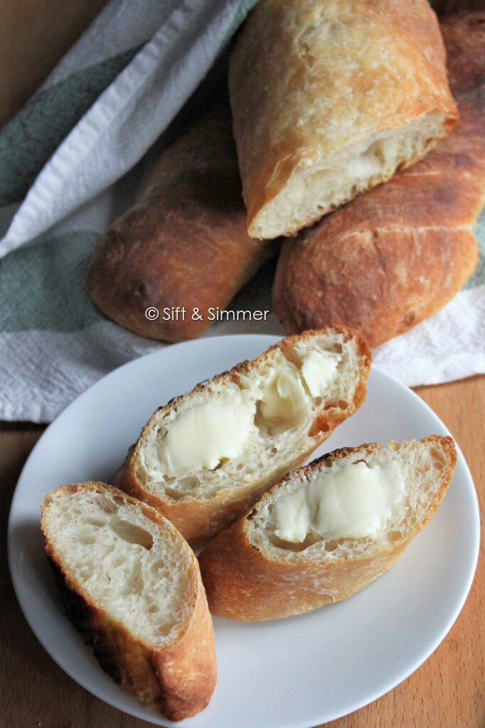 Sliced baguettes with butter smeared on top.