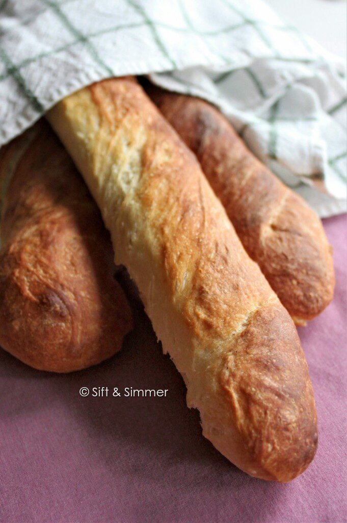 Baguettes under a white and green linen.