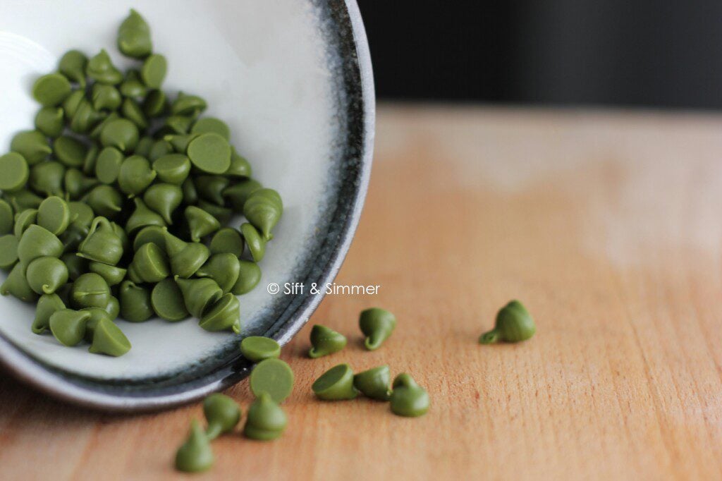 Matcha Chocolate Chips in a bowl, on wooden board.