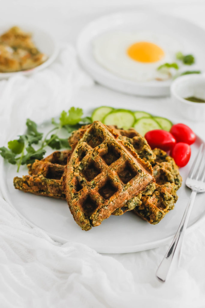 Crispy falafel waffles on white round plate with fork.