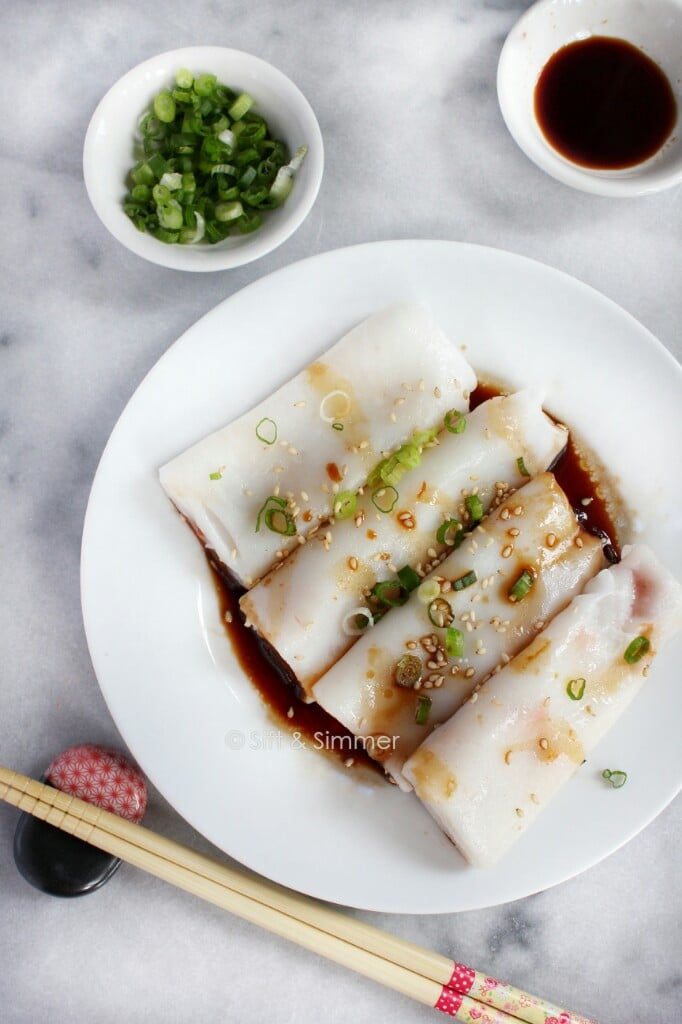  Rouleaux de nouilles de riz sur une assiette blanche, avec des baguettes sur le côté.