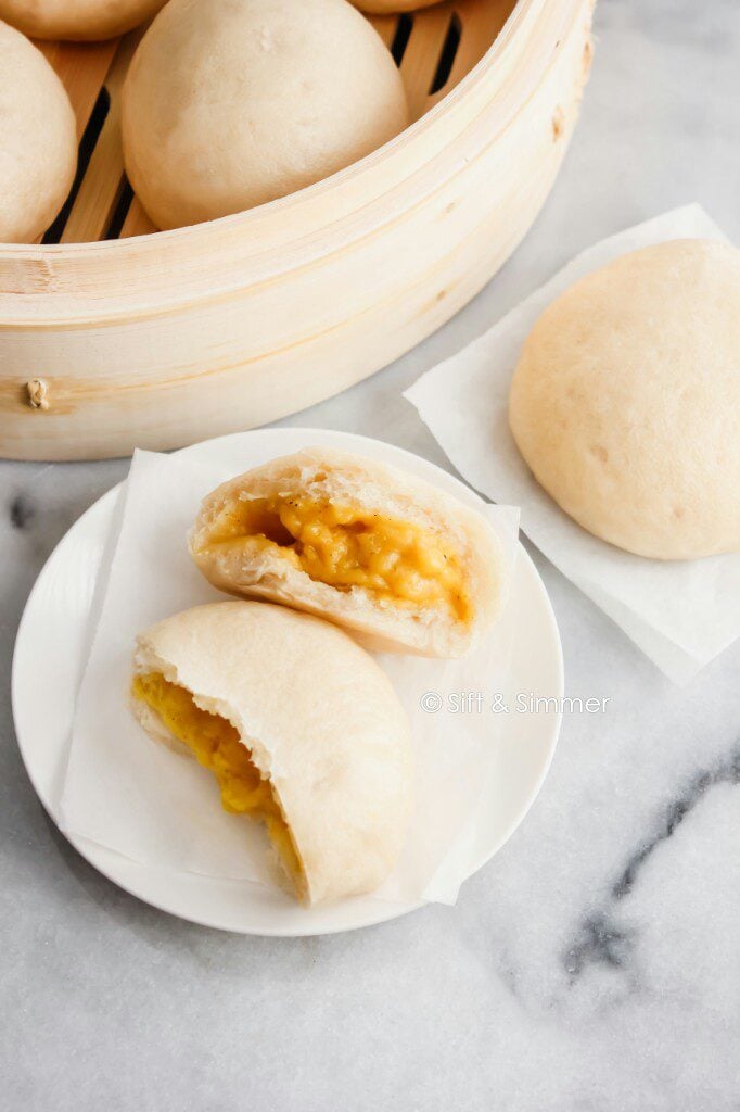 Torn open Custard Buns Lai Wong Bao on white plate.