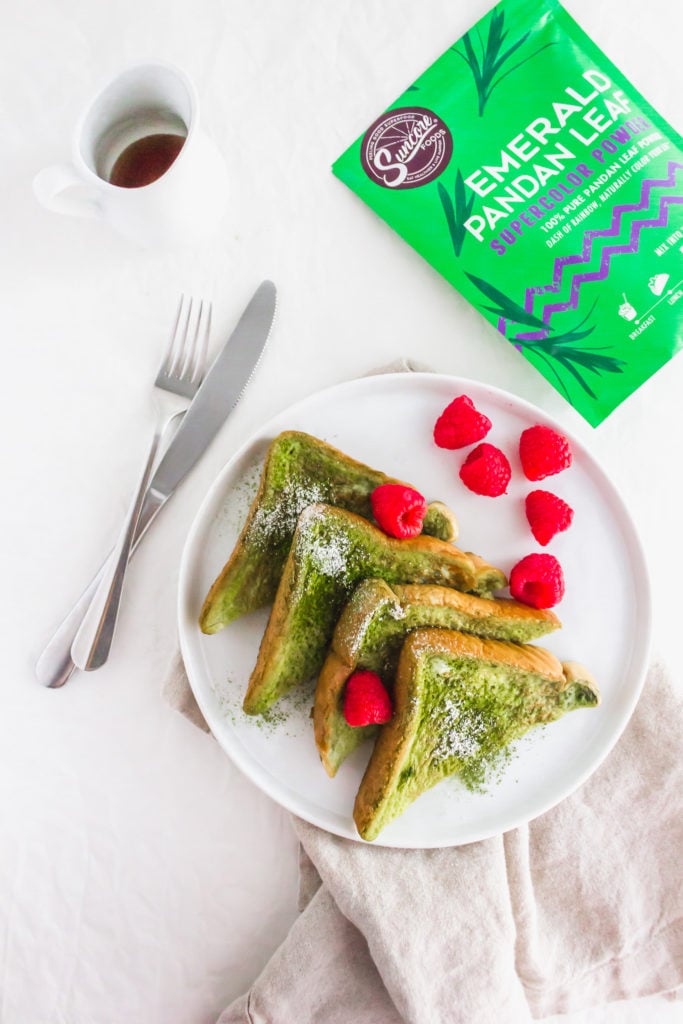 Close up of Pandan French Toast on round white plate with raspberries and fork, packaging on side.