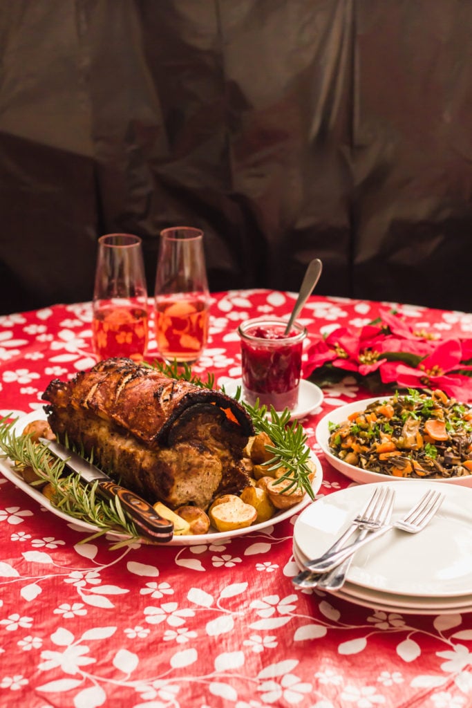 Holiday Roast Pork With Wild Rice Stuffing on table with plates, forks.