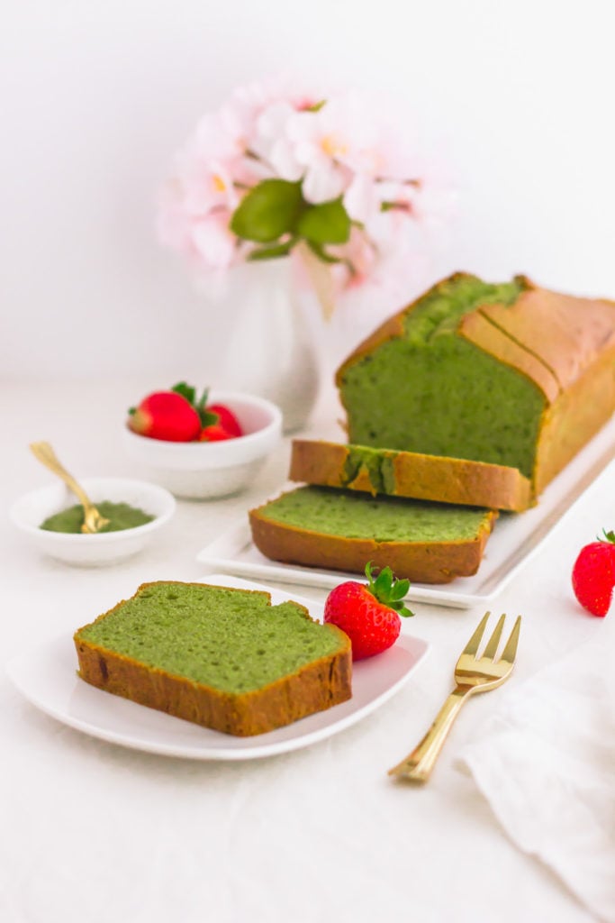 Slice of matcha pound cake on small plate, golden fork on side, cake in background.