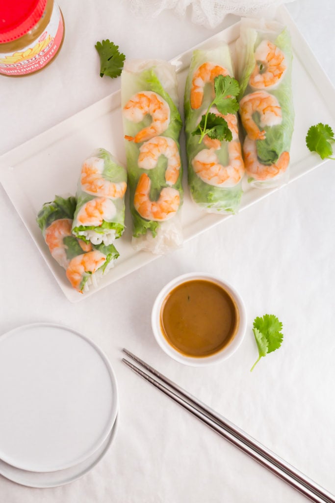 Vietnamese Salad Rolls on white rectangular plate with SunButter Dipping Sauce in small bowl, SunButter jar in background.