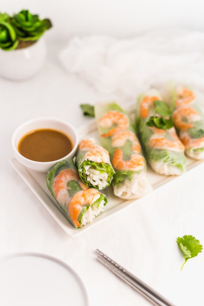 Vietnamese Salad Rolls on white rectangular plate with SunButter Dipping Sauce in small bowl, chopsticks..