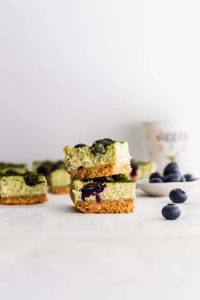 Stack of matcha blueberry cheesecake bars with blueberries on side, siggi's yogurt container in background.