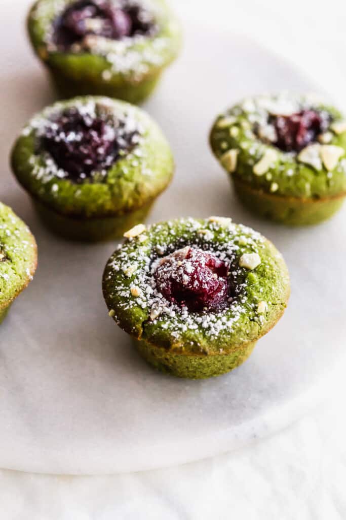 Close up of matcha cherry financiers on a round white trivet.