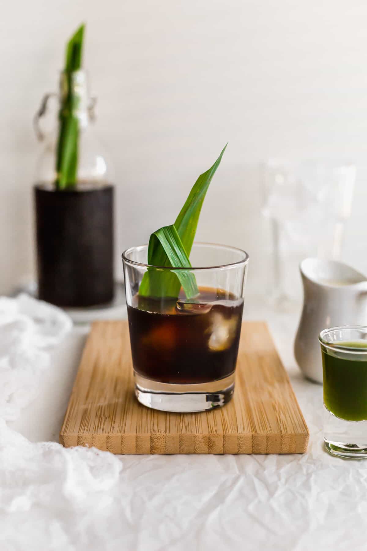 Glass of iced pandan coffee on wooden board.