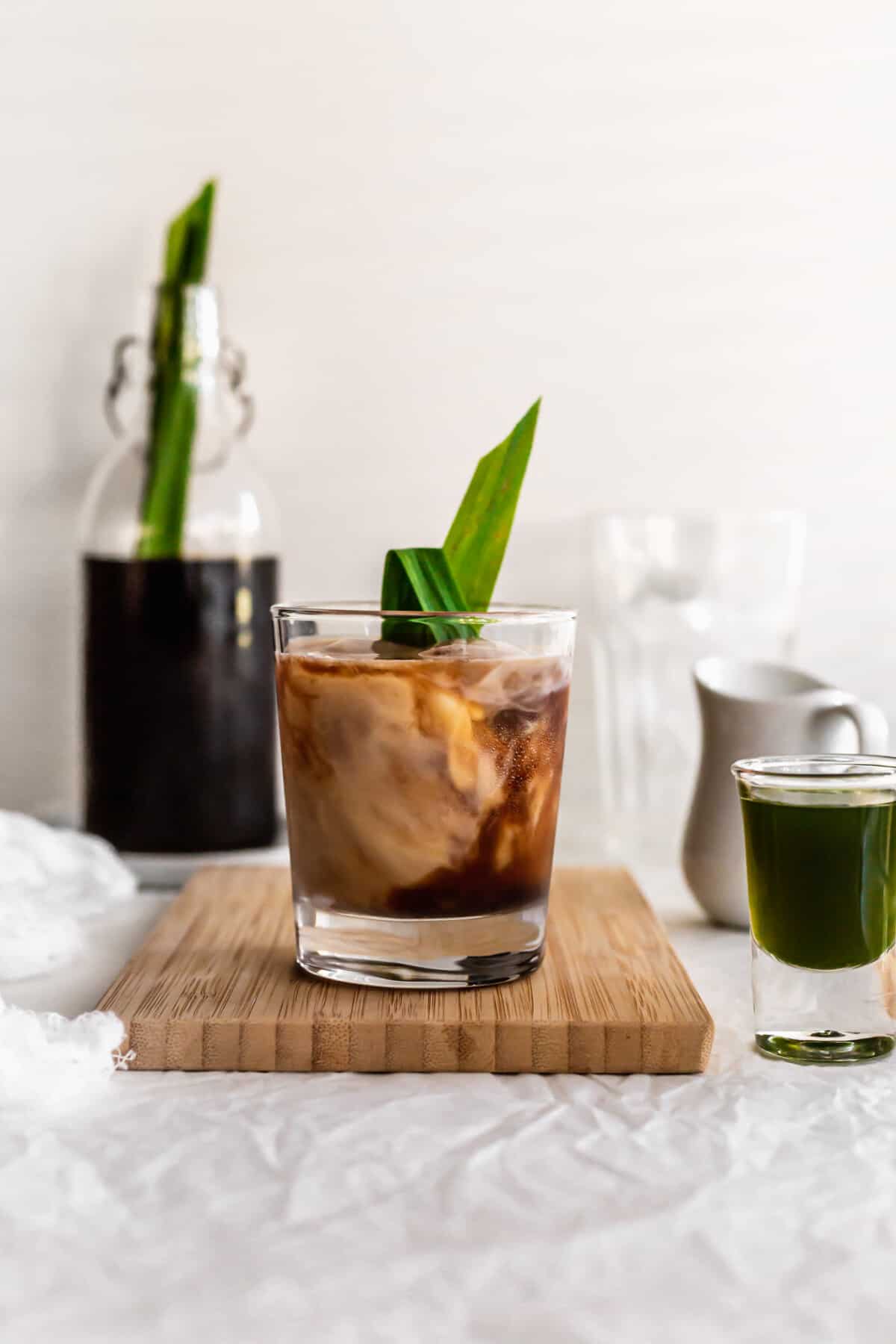 Glass of pandan coffee and milk on wooden board.
