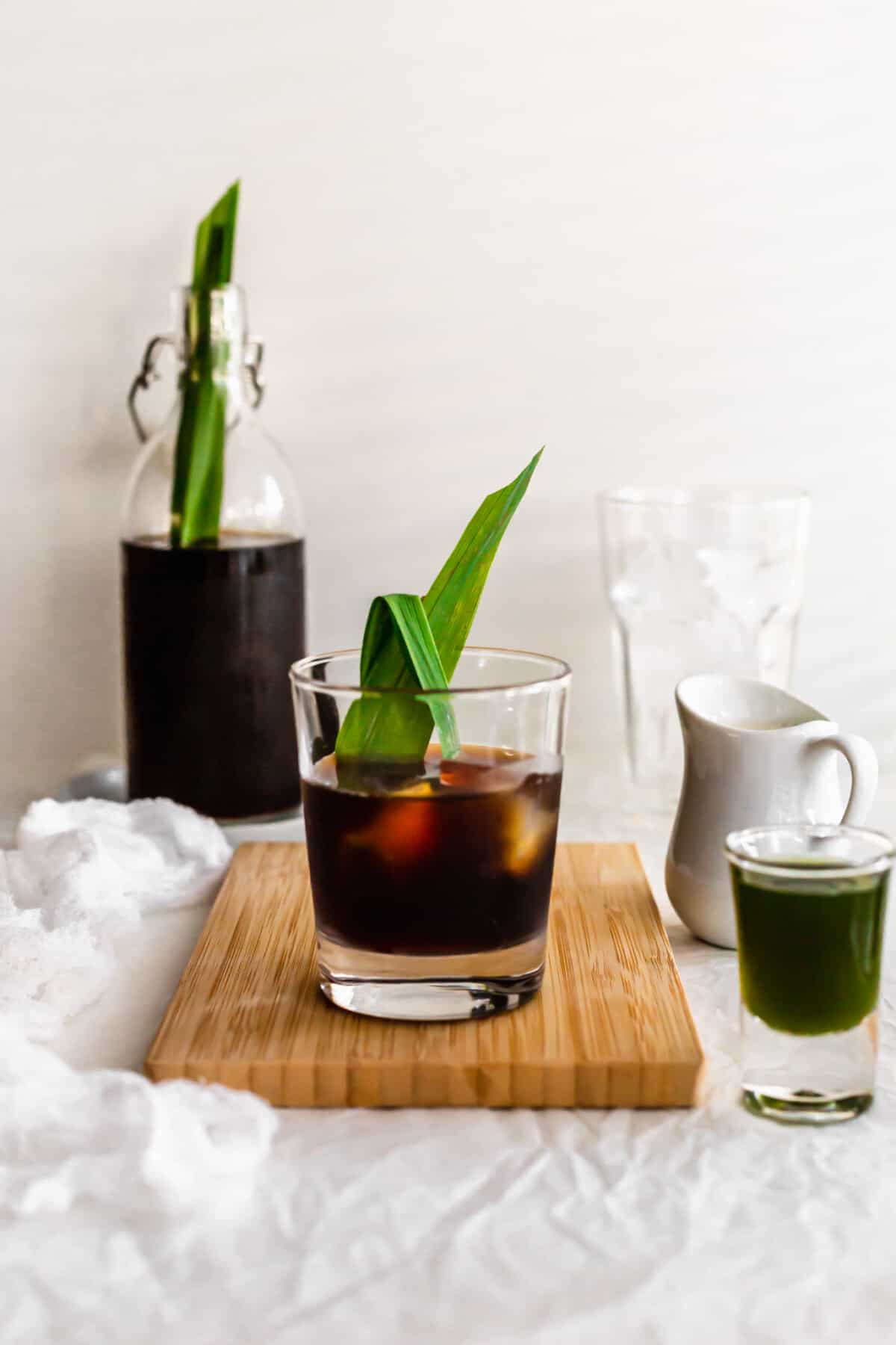 Glass of pandan cold brew coffee on wooden board.