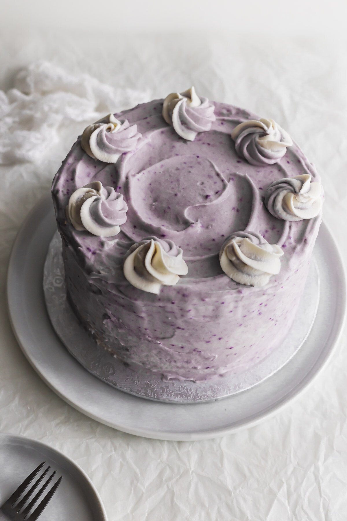Unsliced taro coconut cake on a white plate.