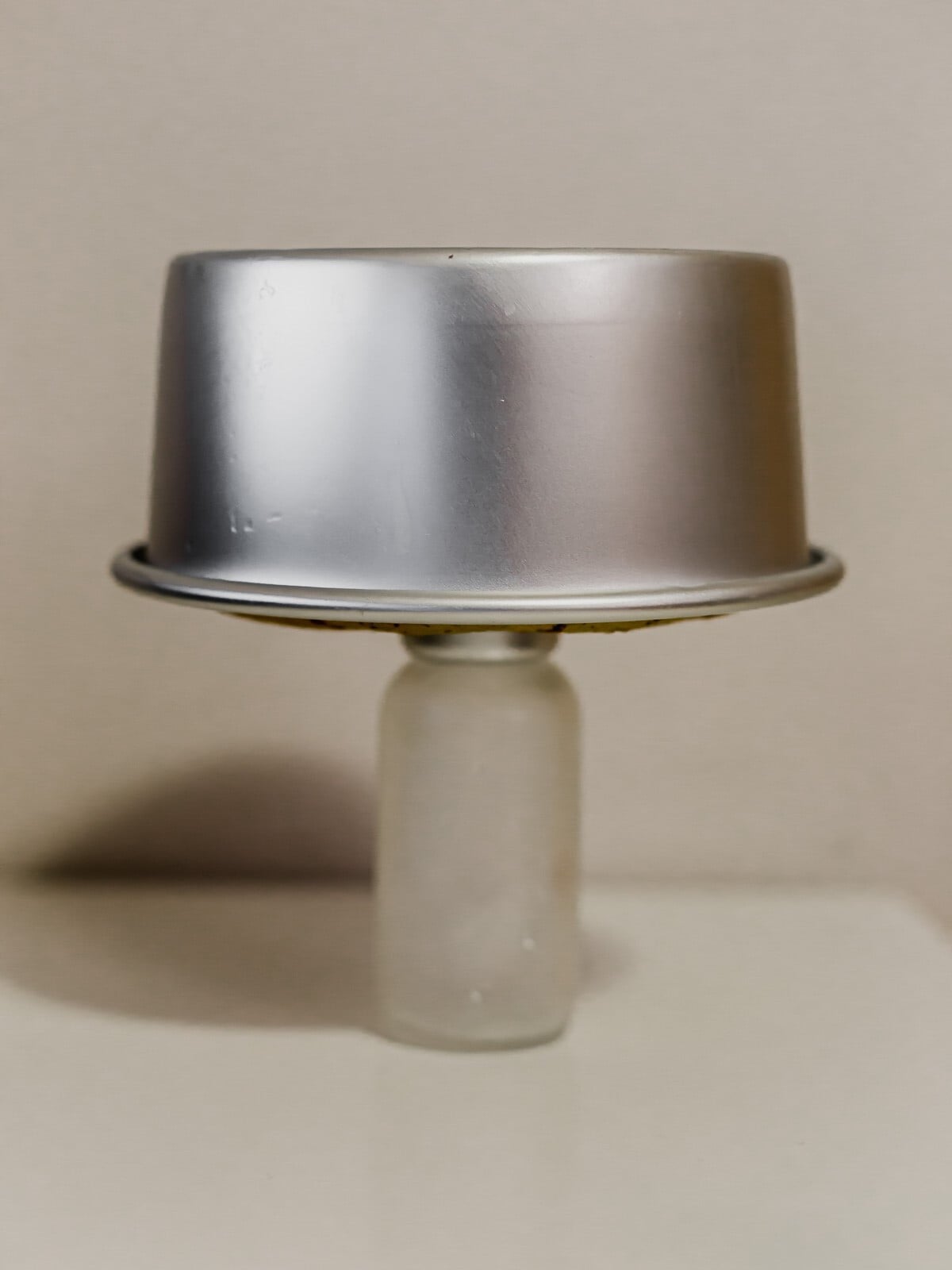 Chiffon cake tin cooling upside down on a bottle.