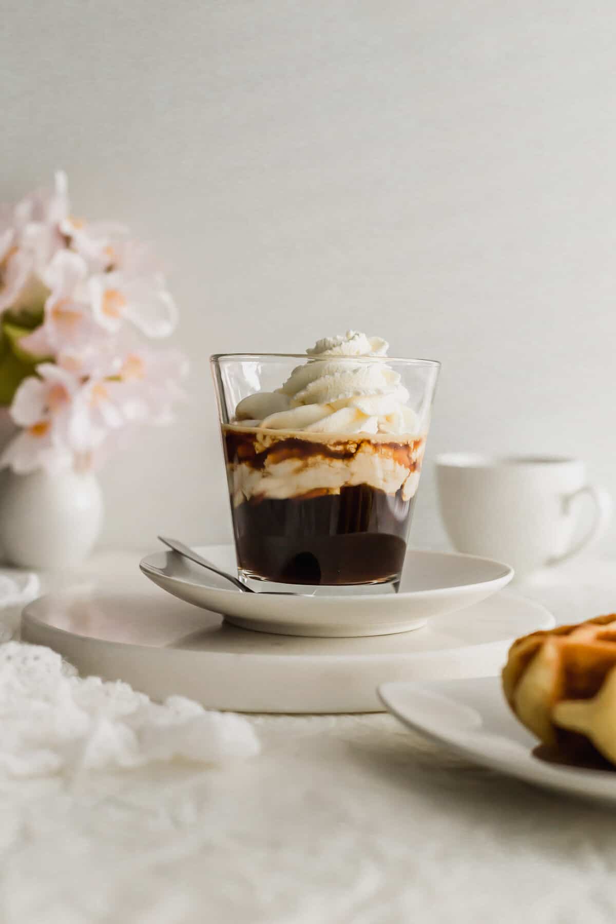 Espresso con panna in a glass with spoon on the side.