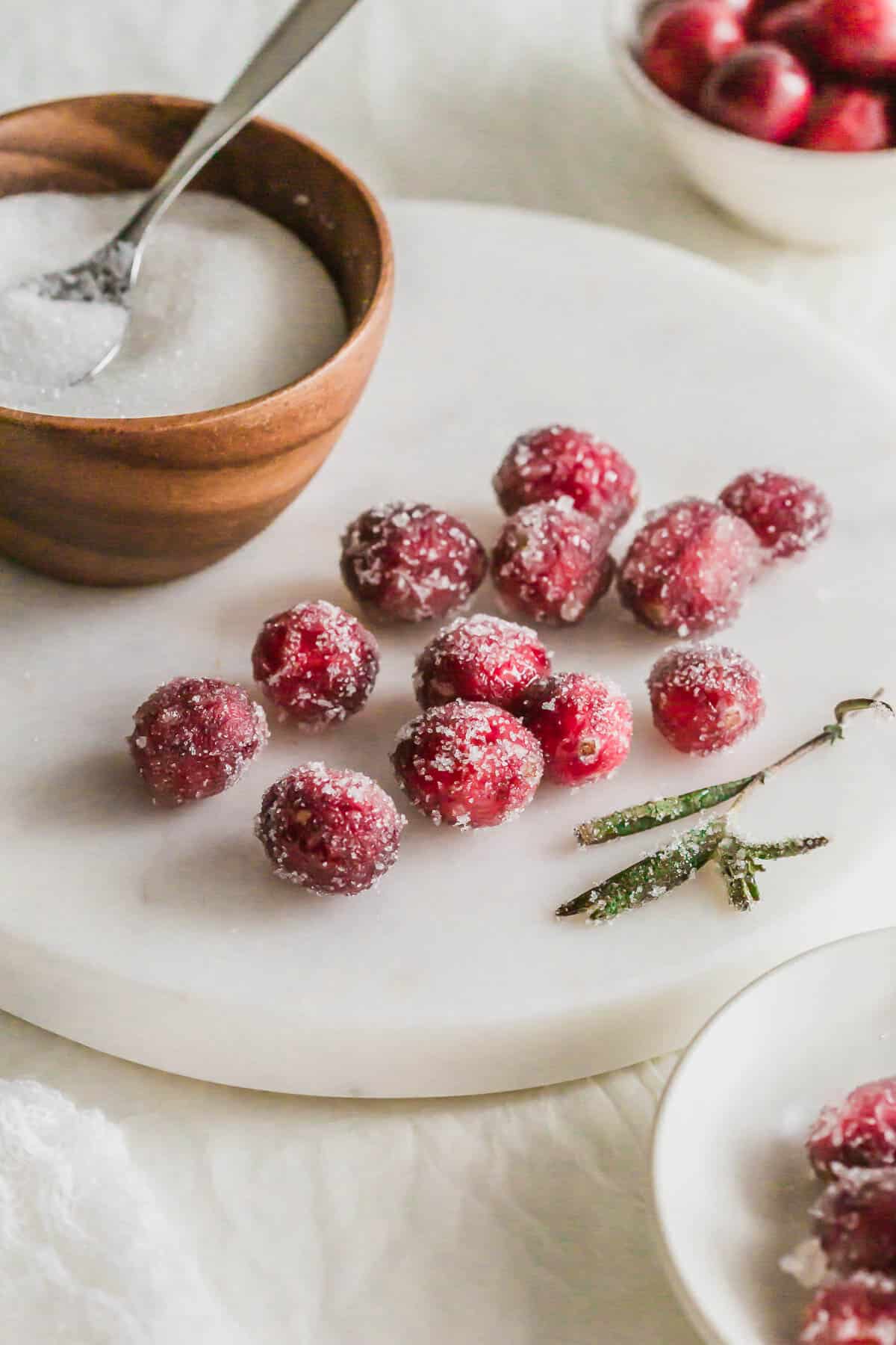 Close up of sugared cranberries on a white round marble.
