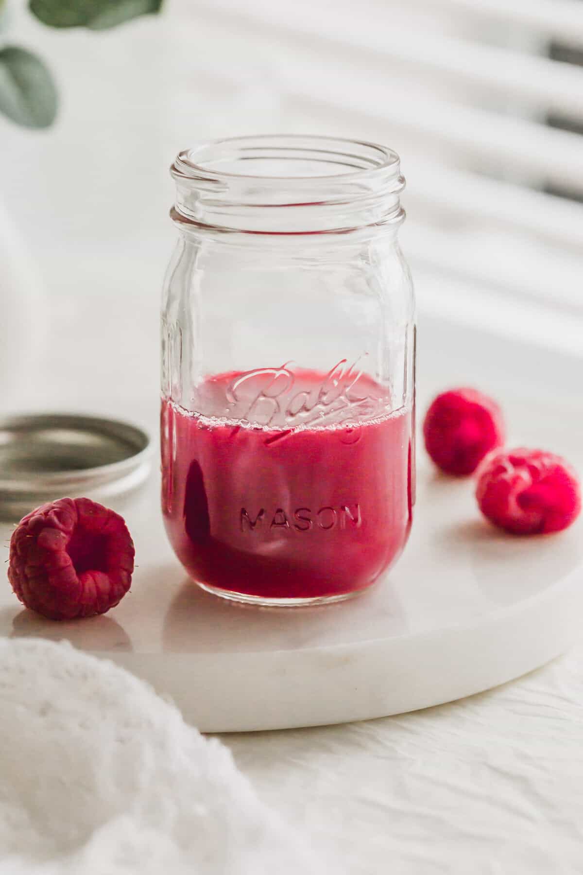 A glass half filled with raspberry syrup.