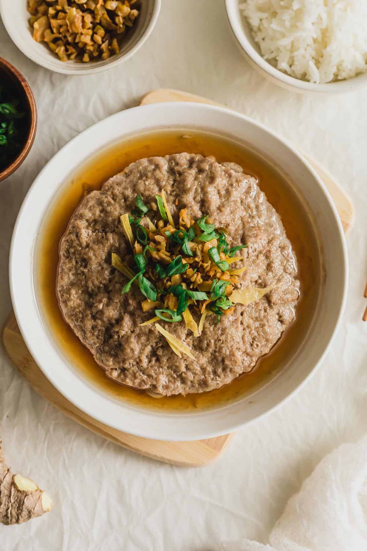 Chinese steamed pork patty in a white plate on wooden board.