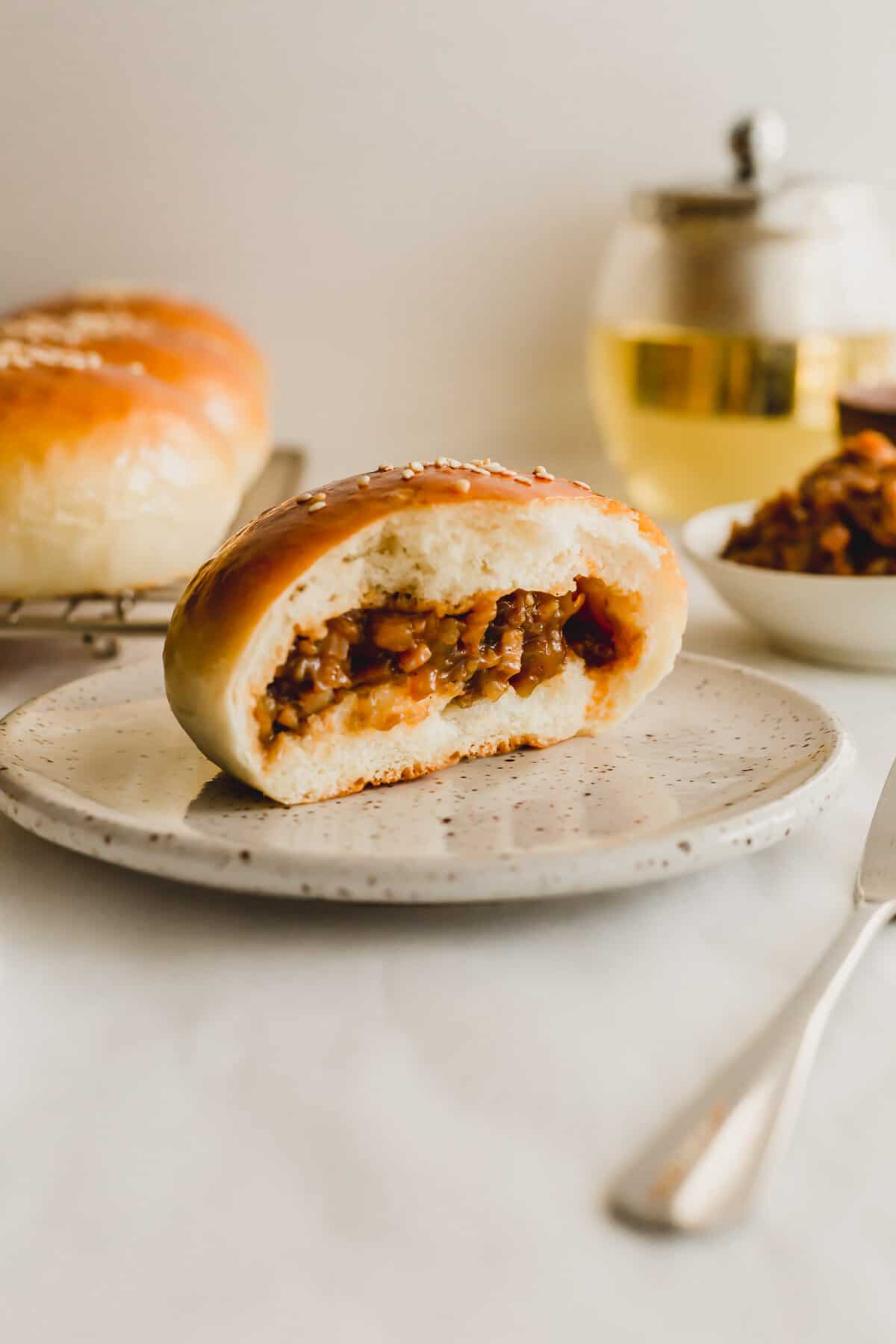 A cut open bbq pork bun on a speckled plate.