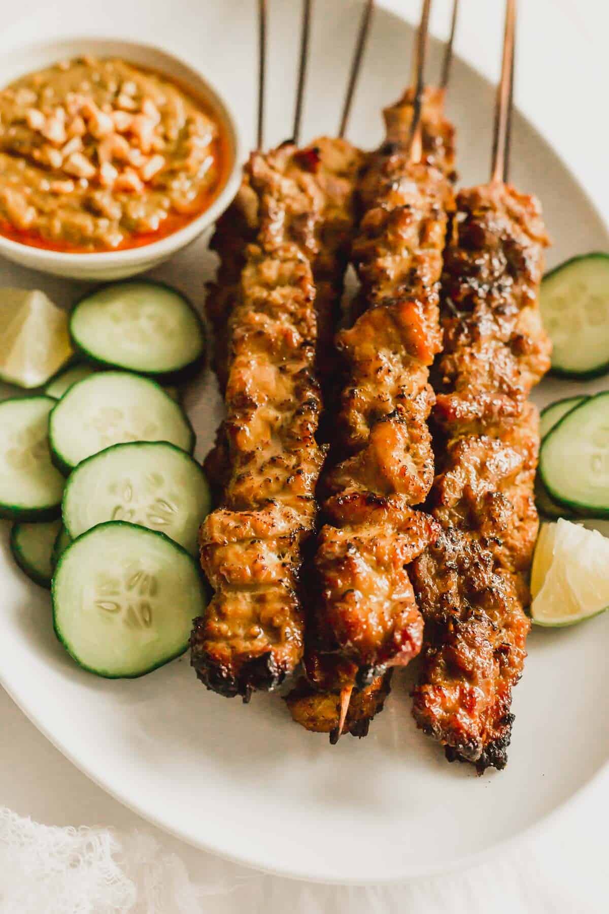 Pork satay skewers on a white oval plate.