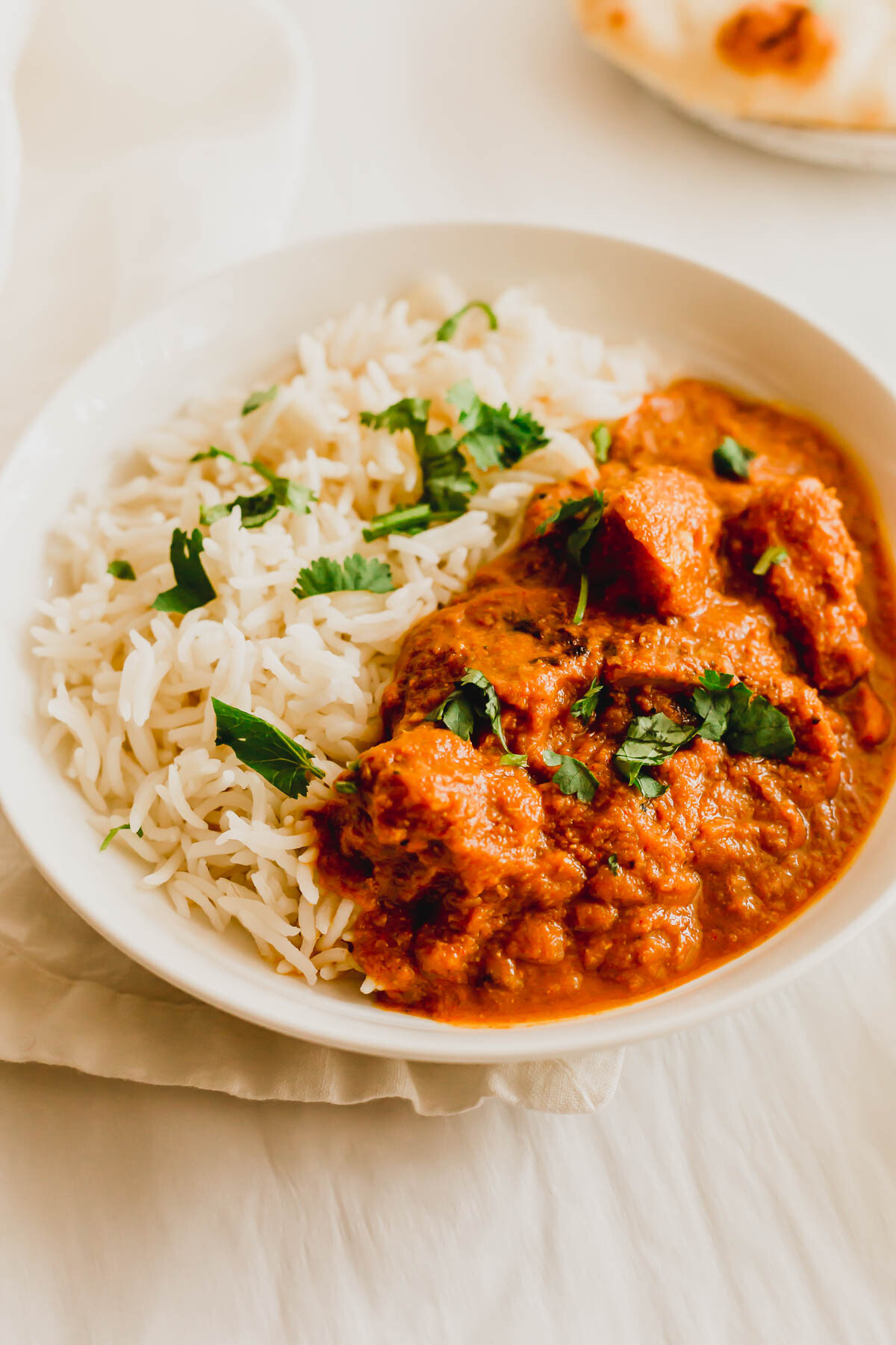 Chicken tikka masala with rice in a white dish.