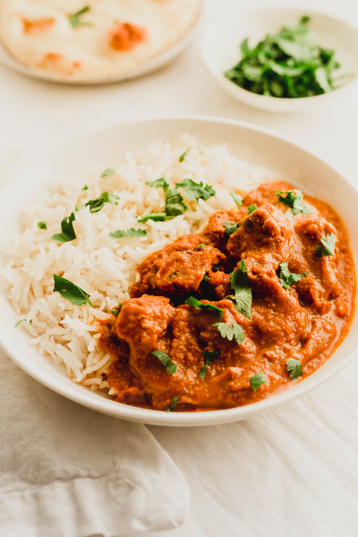Chicken tikka masala with rice in a white dish.