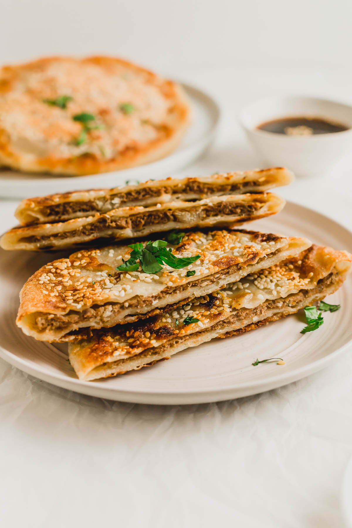 Cut, crispy Chinese beef pancakes piled on a beige plate.
