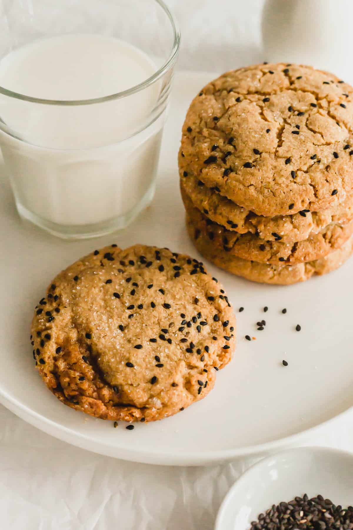 Tahini miso cookies on white plate with a glass of milk.