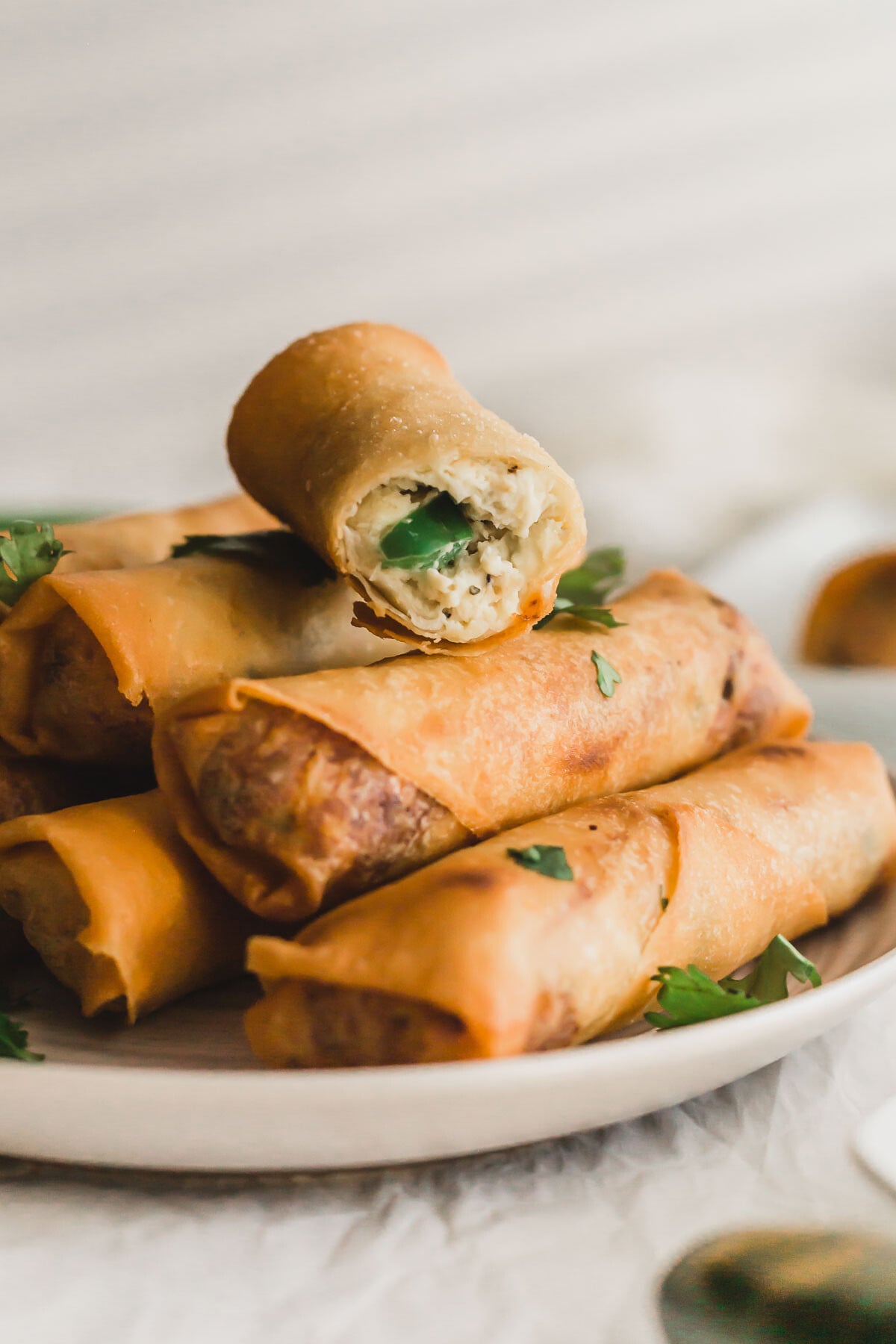 A close up of a cut Jalapeno chicken egg rolls on a small white plate.