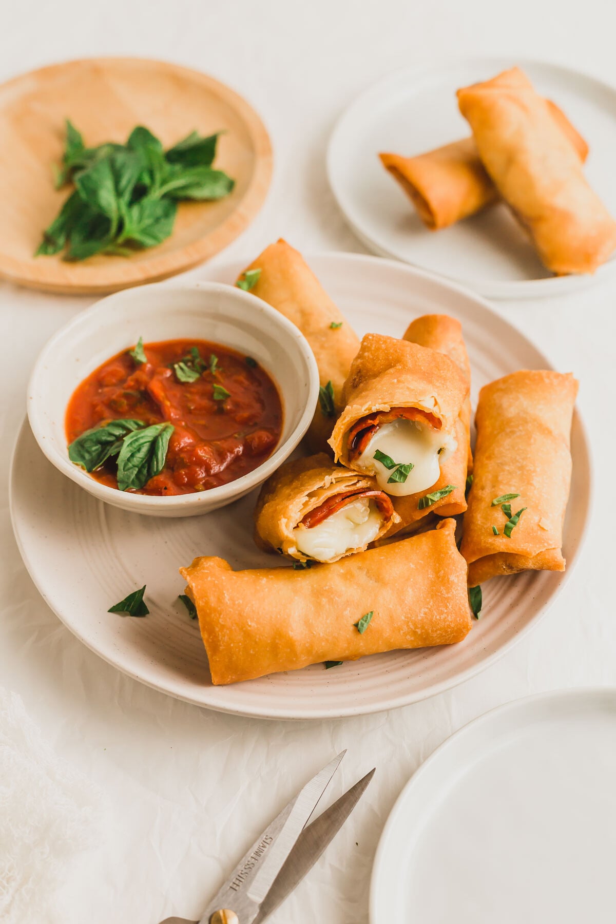 Pizza egg rolls on a plate, with tomato marinara sauce on the side.