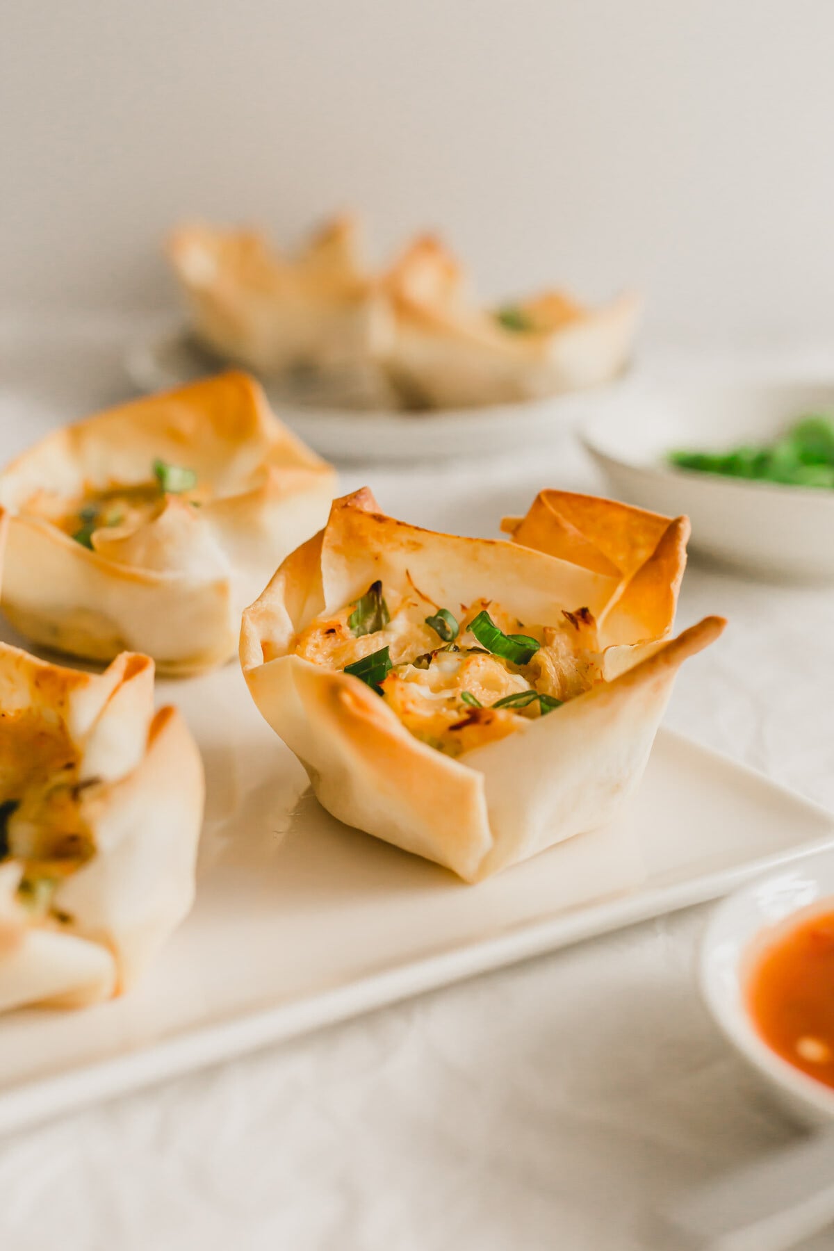 Open-faced baked crab rangoons on a square white plate.