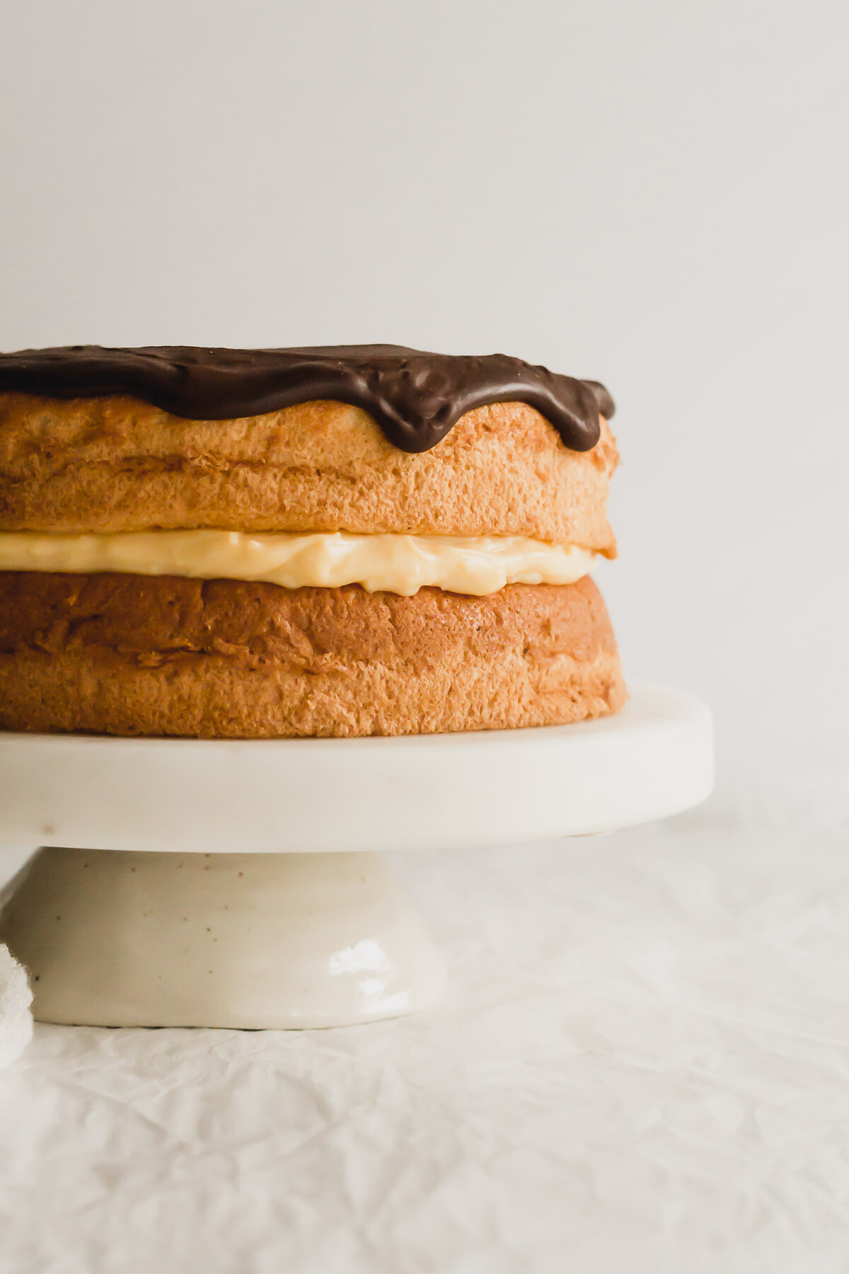 Boston cream pie on a white cake stand.