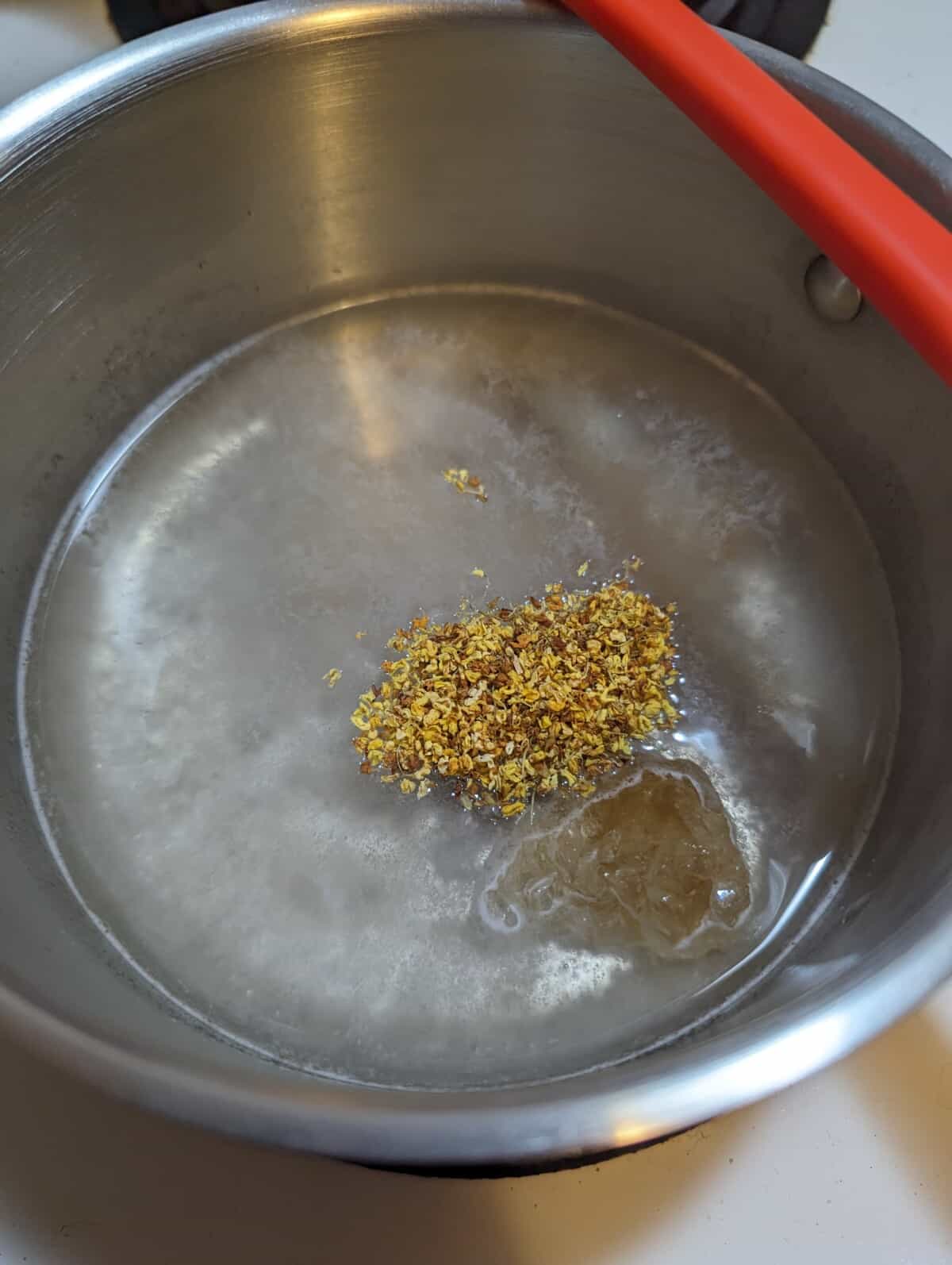 Osmanthus flowers added to agar mixture in saucepot.