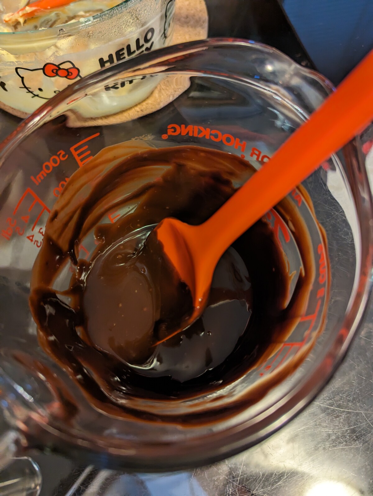 Chocolate ganache in a measuring cup, with spatula.