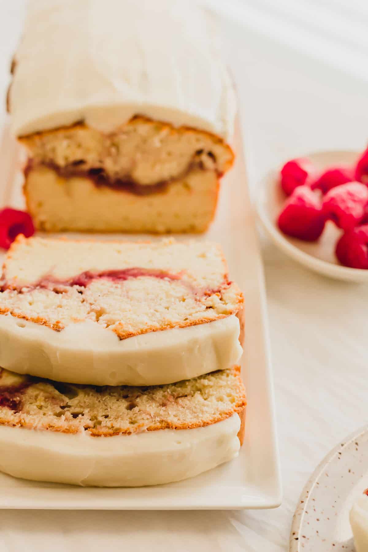 Slices of raspberry lemon cake on a white rectangular plate.