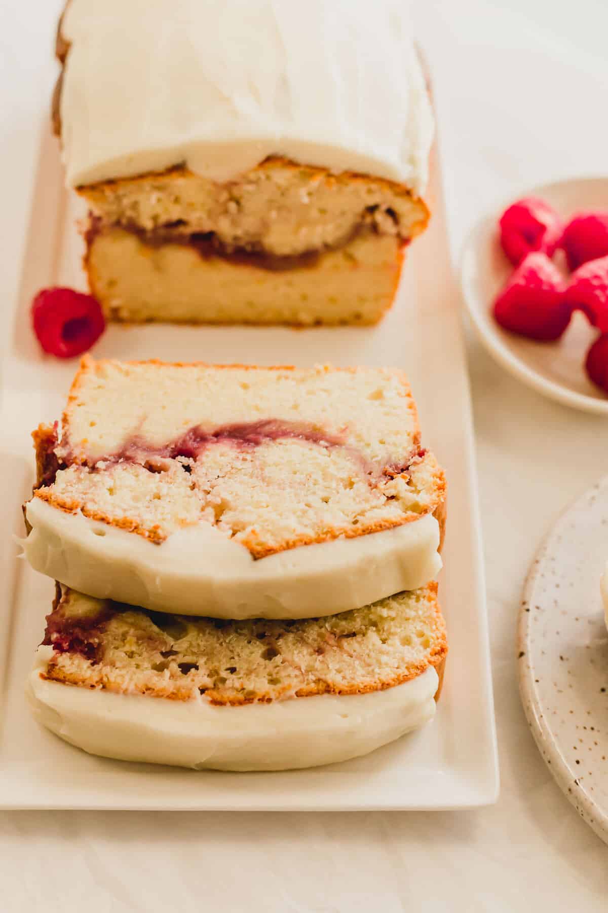 Slices of raspberry lemon loaf cake laid on a white rectangular plate.