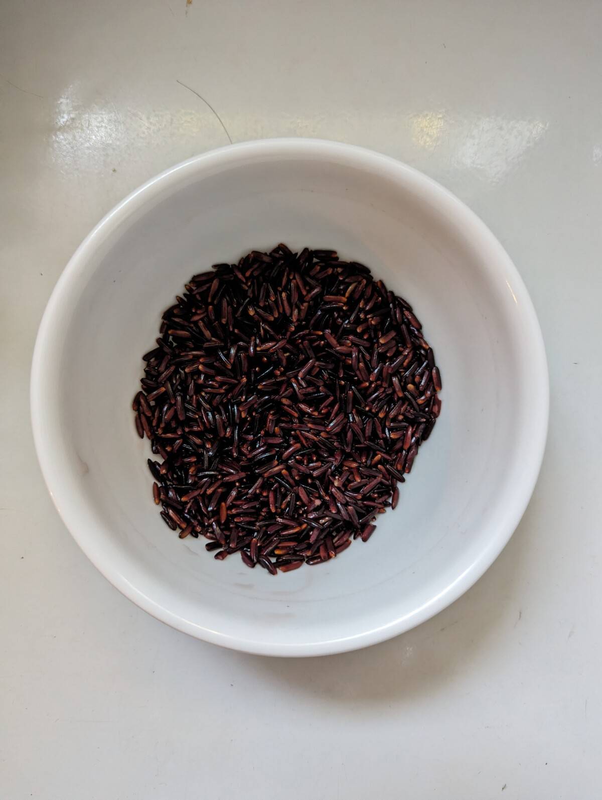 Black glutinous rice in a white bowl.