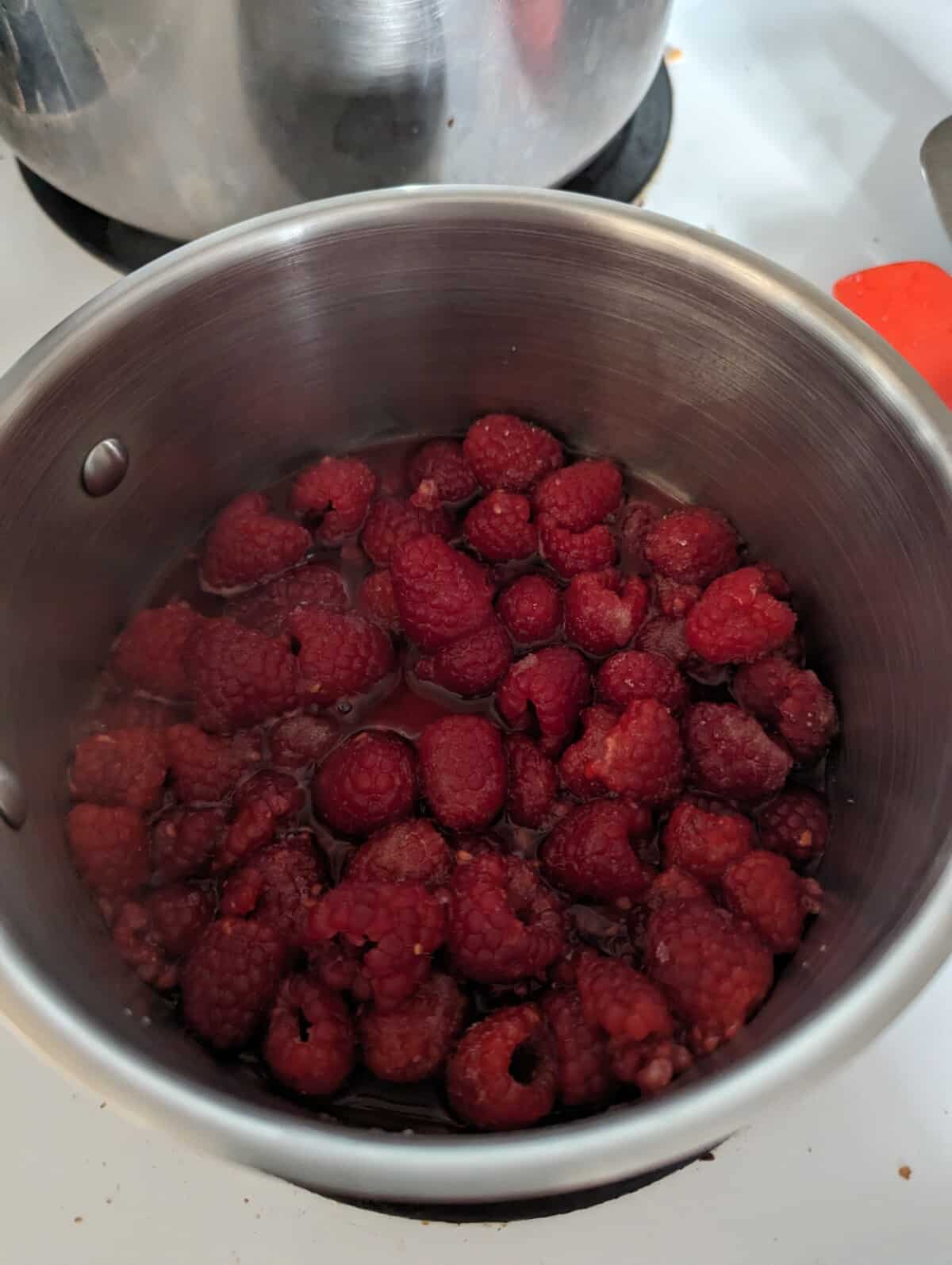 Softened raspberries in a metal saucepan.