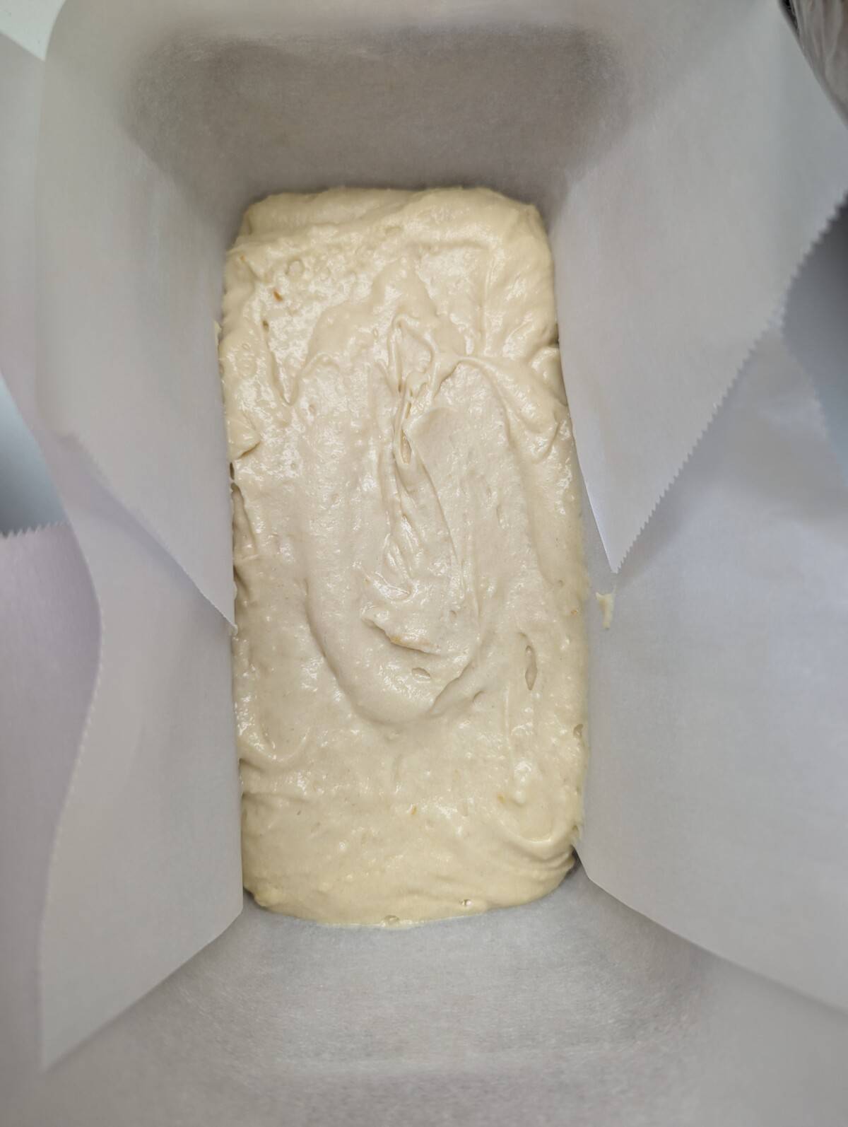 Plain cake layer in a lined loaf pan.