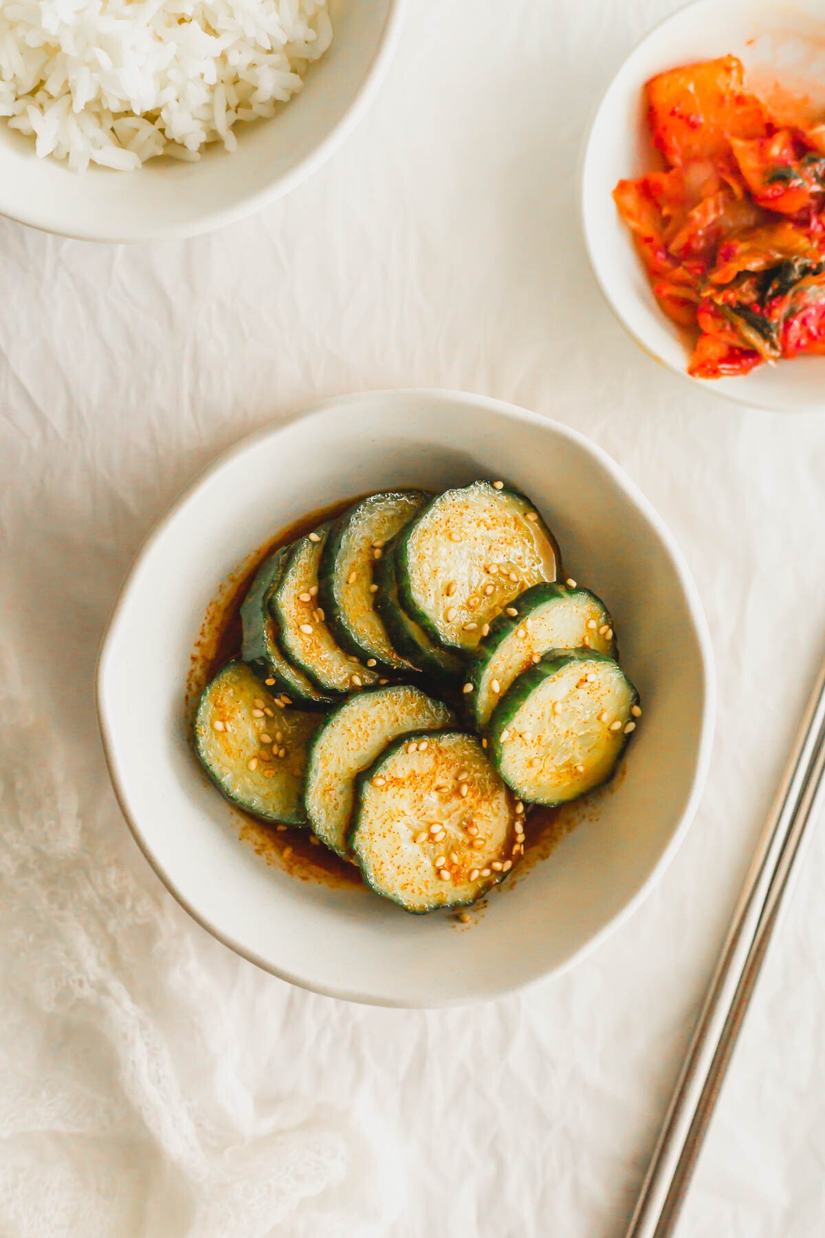 Sliced cucumbers dressed with seasonings in a white bowl.