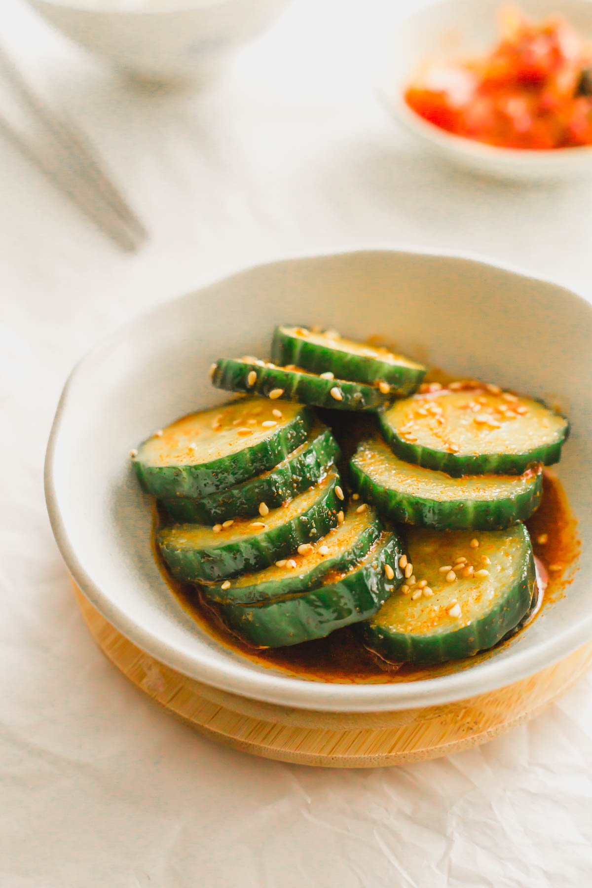 Sliced cucumbers in chili oil in a white bowl.