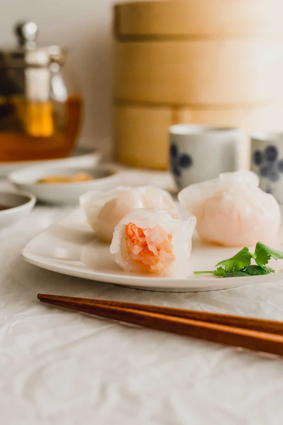 Close up of a bitten shrimp dumpling on white plate.
