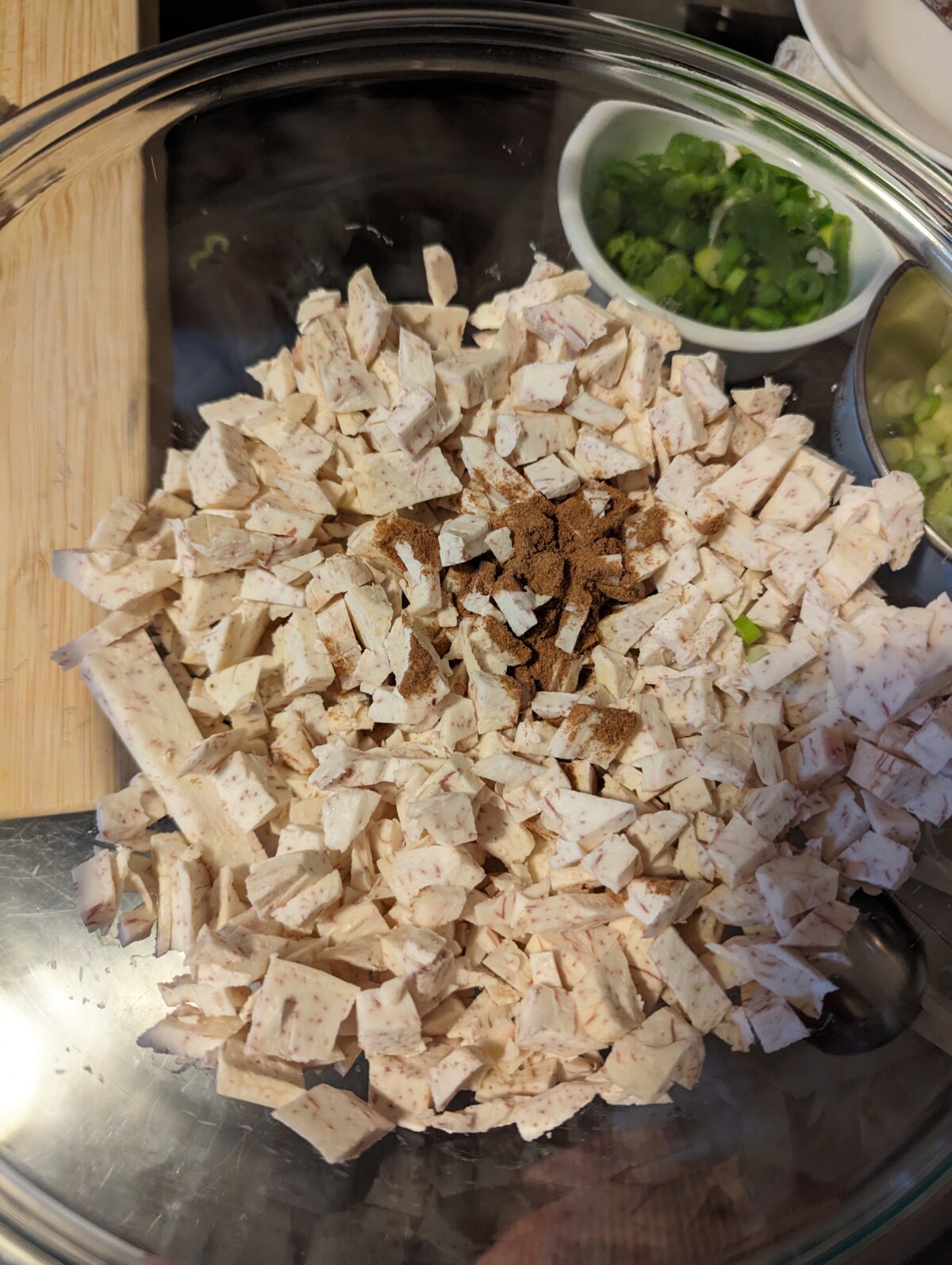 Cut up taro with spices in a glass bowl.