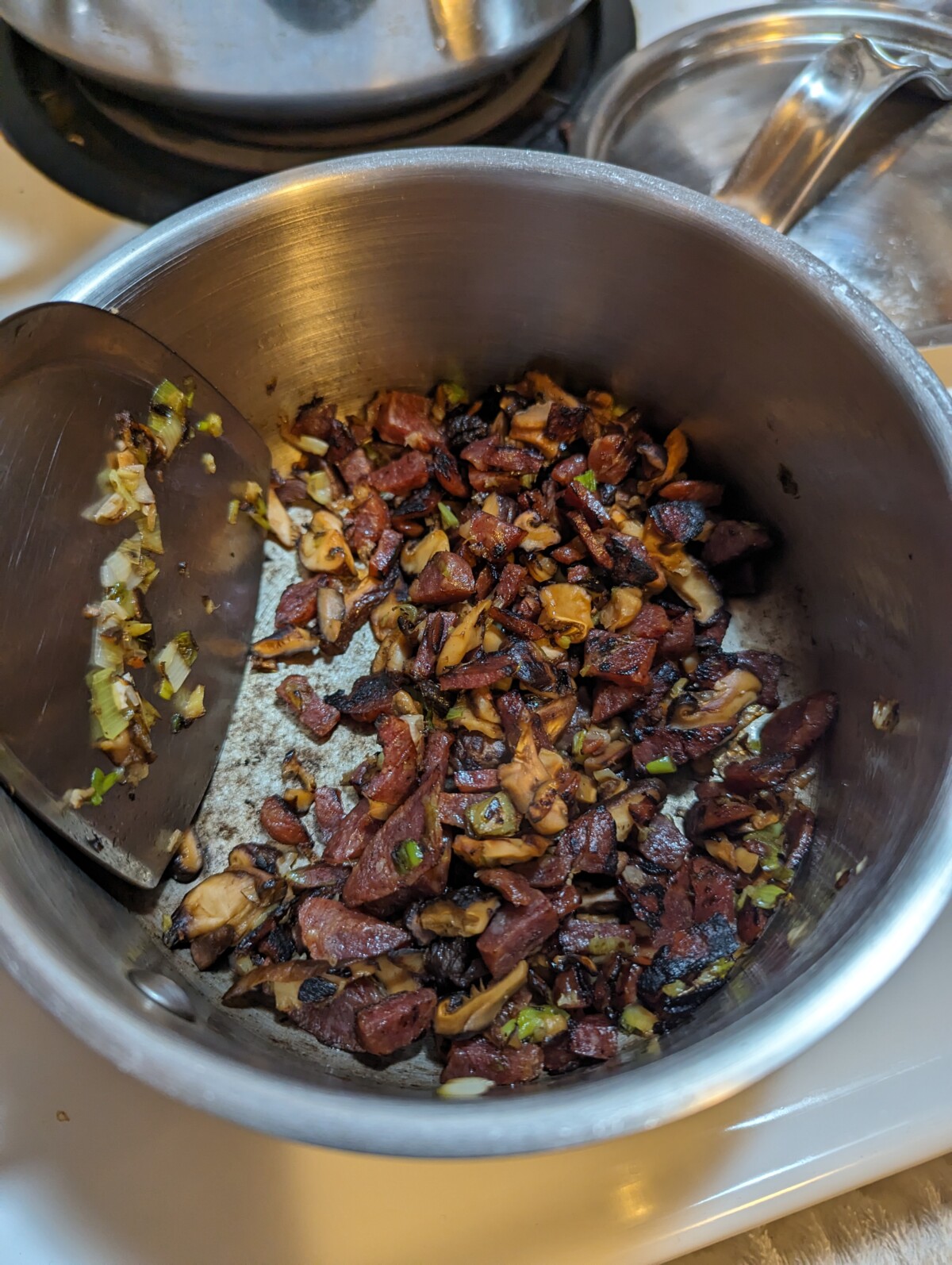Sauteing aromatics and Chinese sausage in a pot.