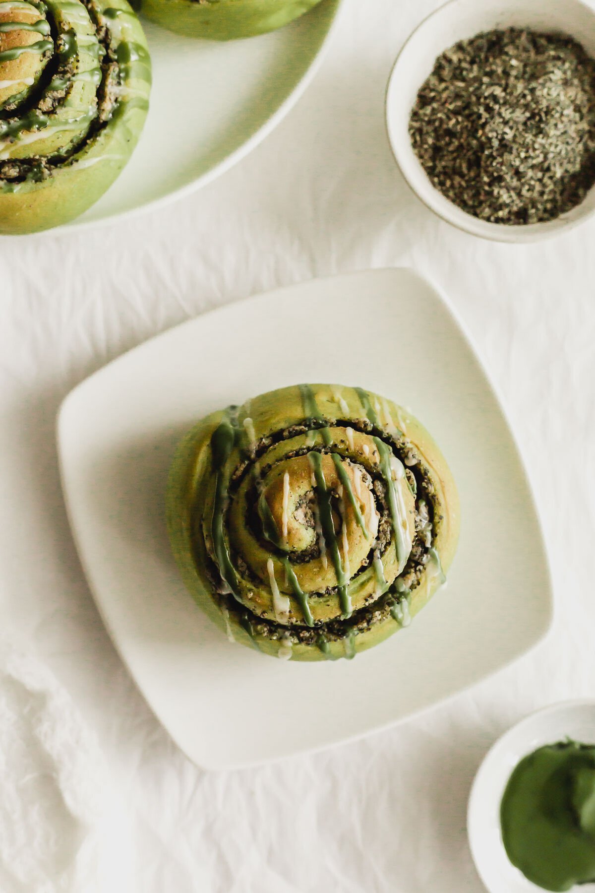 Matcha cinnamon roll on a white square plate.