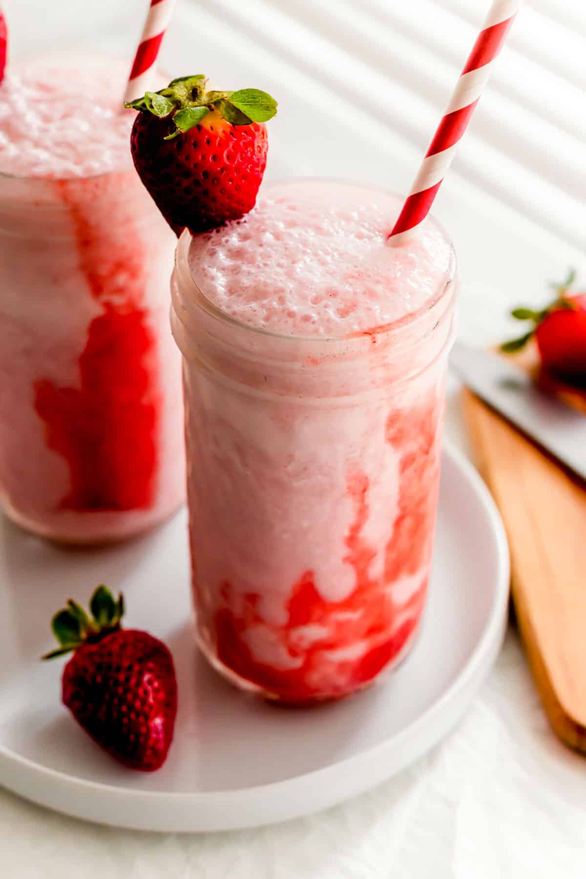 Two glasses of Korean strawberry milk with straws.