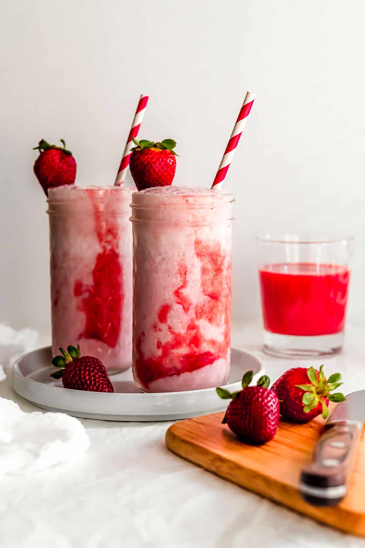 Two glasses of Korean strawberry milk with straws.