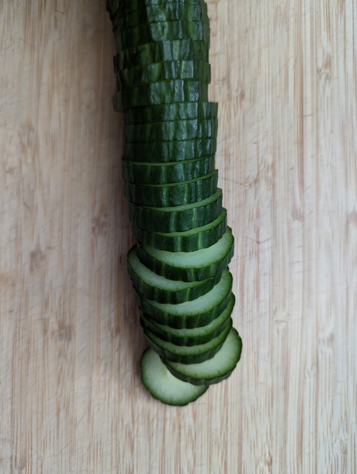 Sliced cucumbers on a wooden board.