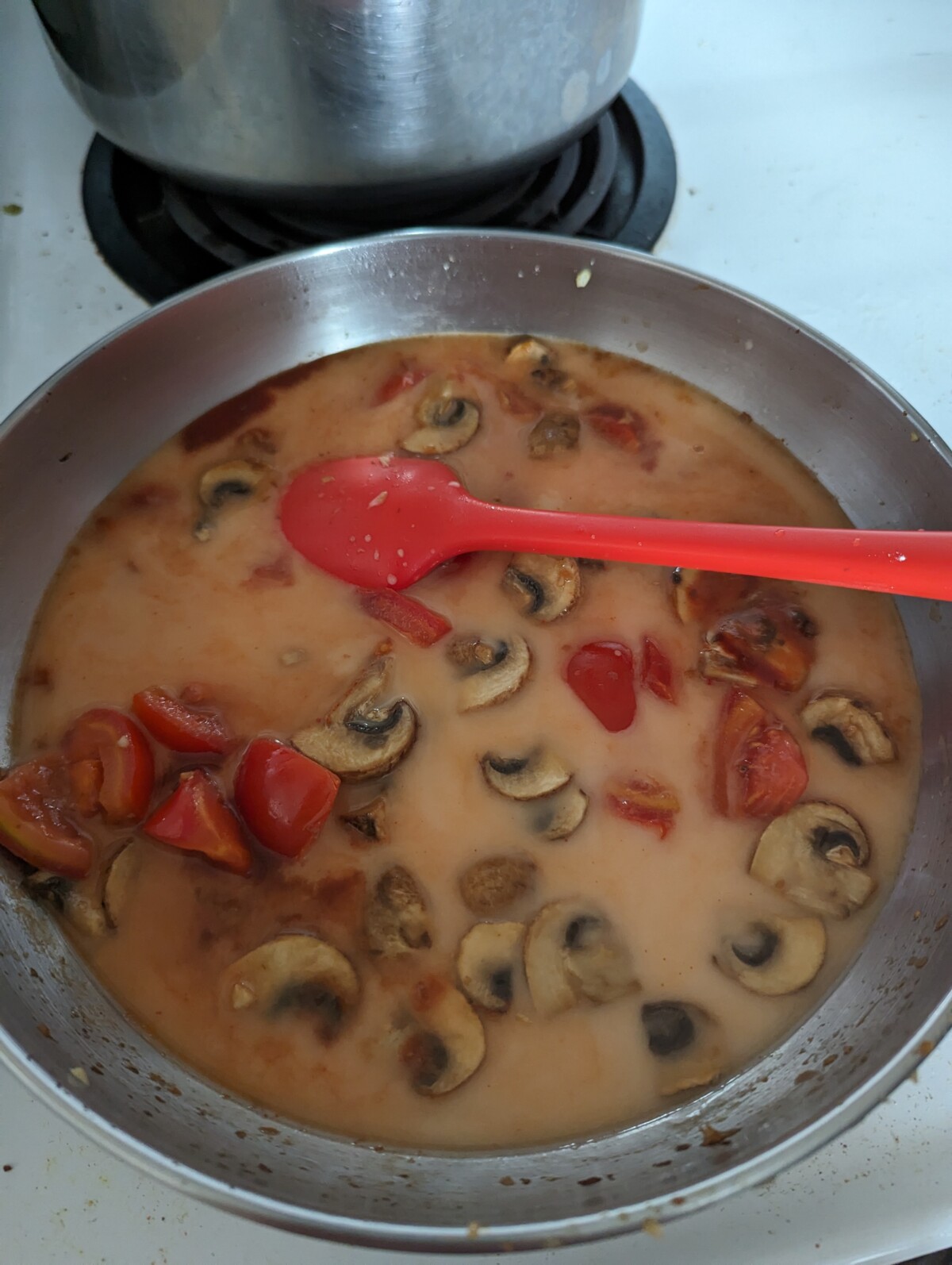 A frying pan filled with veggies and sauce.